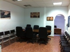 Foto de nuestra sala de juntas. Se puede ver una mesa de juntas con 6 sillones de despacho y varias sillas a lo largo de la sala.